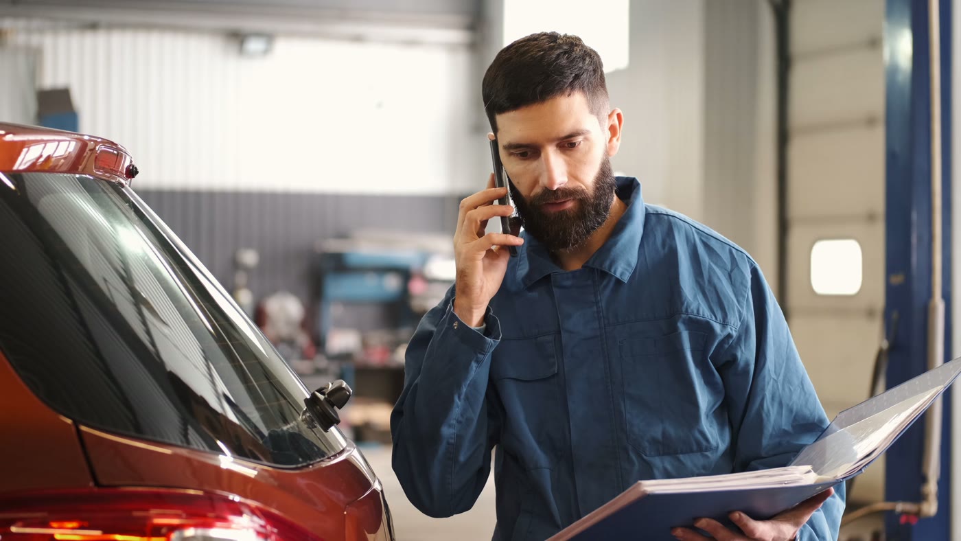 A business owner on the phone in his shop, reviewing paperwork
